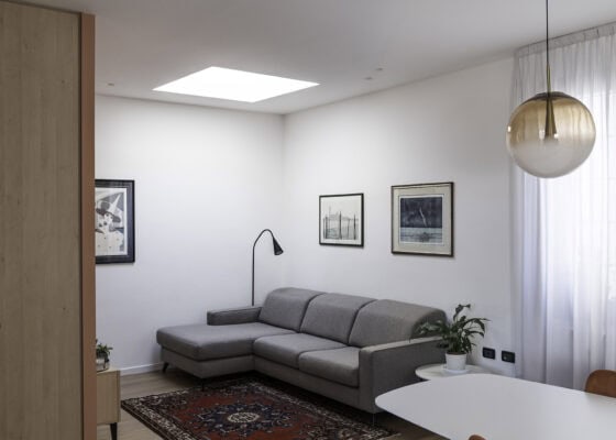 Zona giorno con grande divano angolare, tappeto persiano e lucernario in un appartamento ristrutturato a Piove di Sacco (Padova)