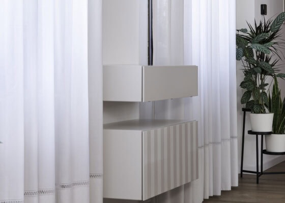 Mobile sospeso su misura con piano in legno, piante e tendaggi chiari nella zona giorno di un appartamento